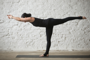 Young yogi attractive woman in Warrior three pose, loft background